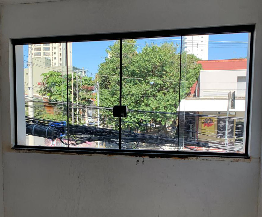 Janela em vidro com esquadria escura instalada em ambiente residencial