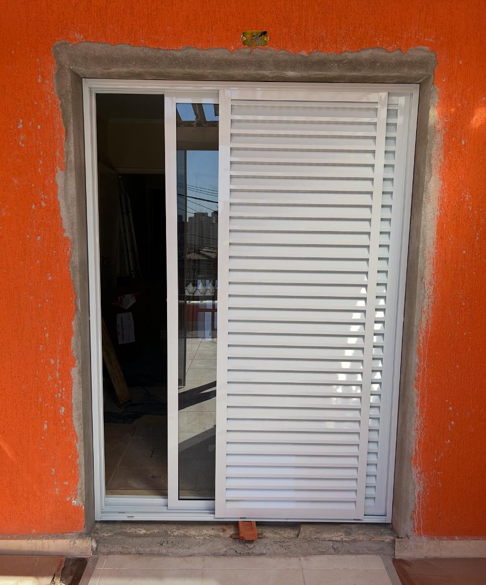 Porta veneziana instalada em parede laranja